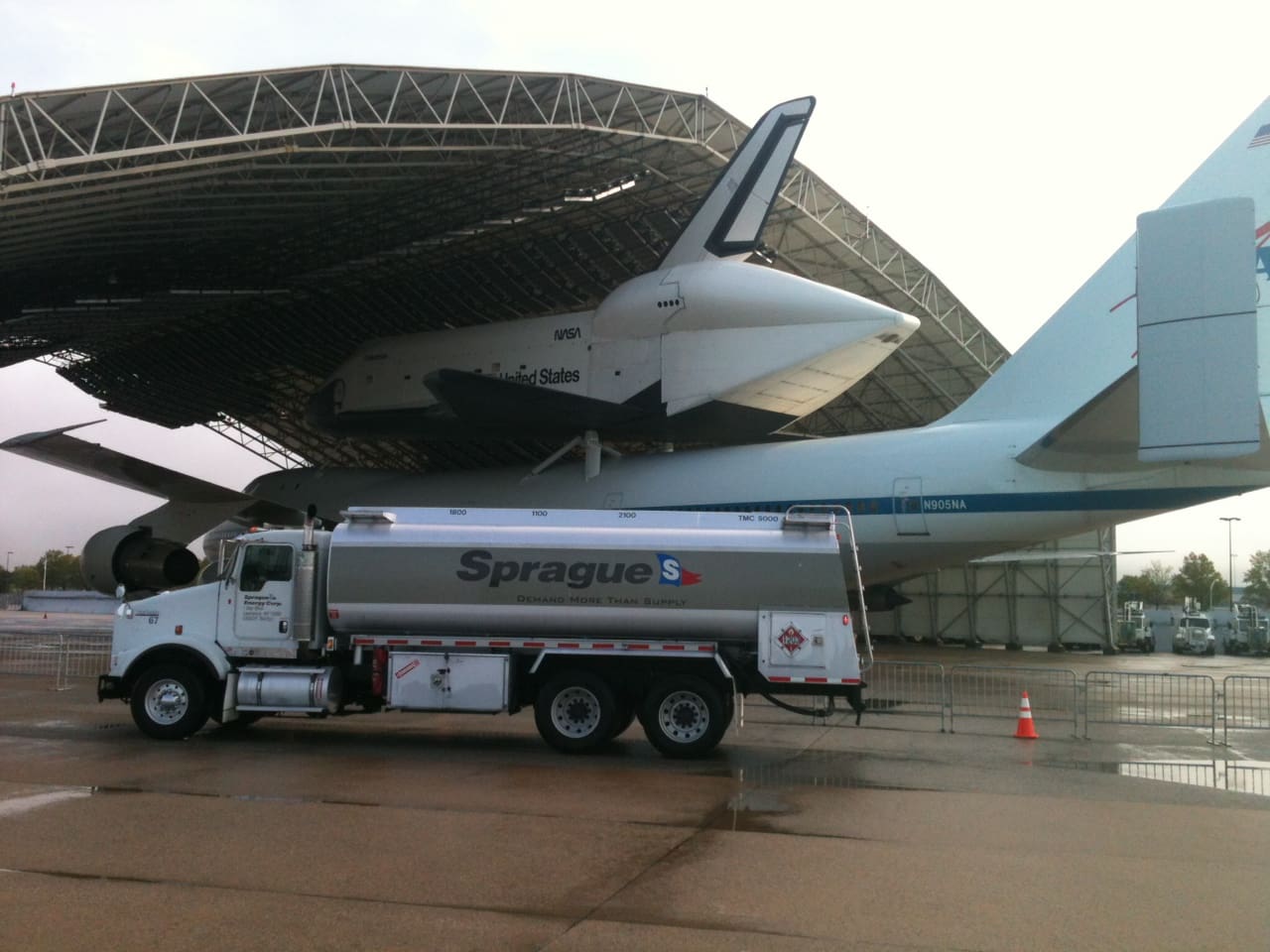 Sprague Energy fuel truck parked in front of a large aircraft transporting a space shuttle, highlighting support for aerospace and specialized fueling needs.