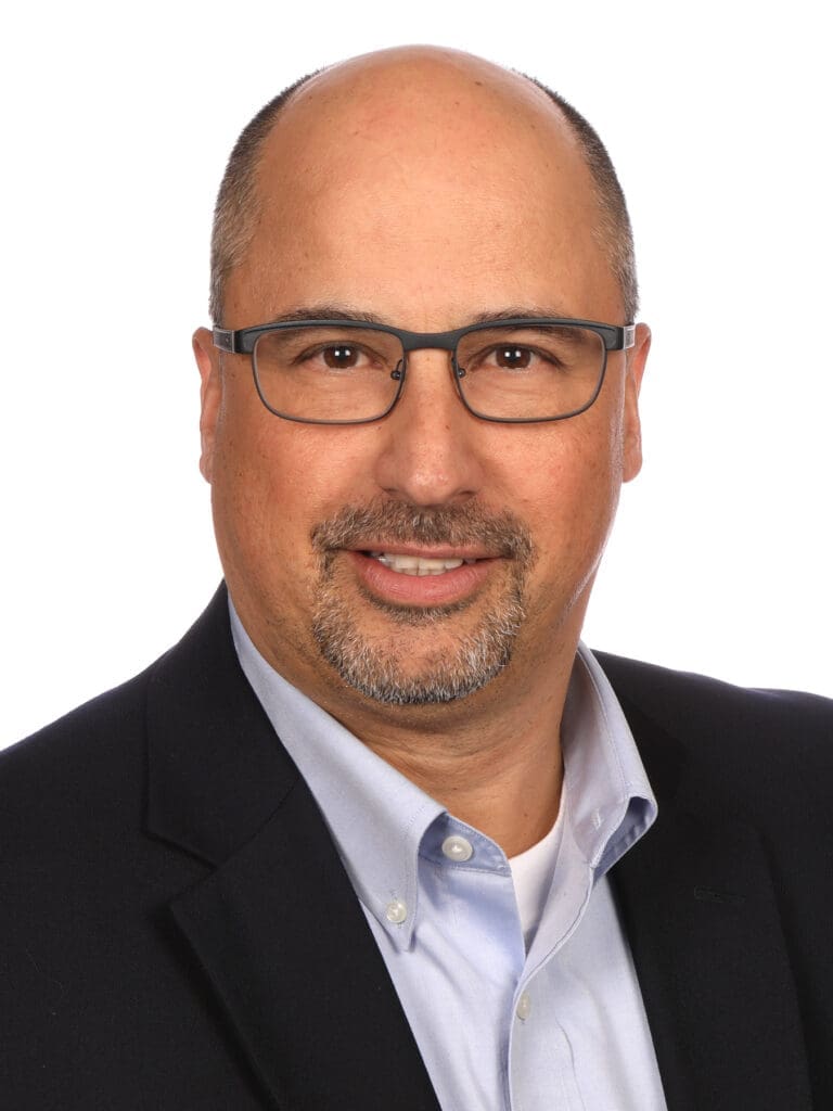 Headshot of Jacques Ferraro, wearing glasses and a blazer, posed against a white background.
