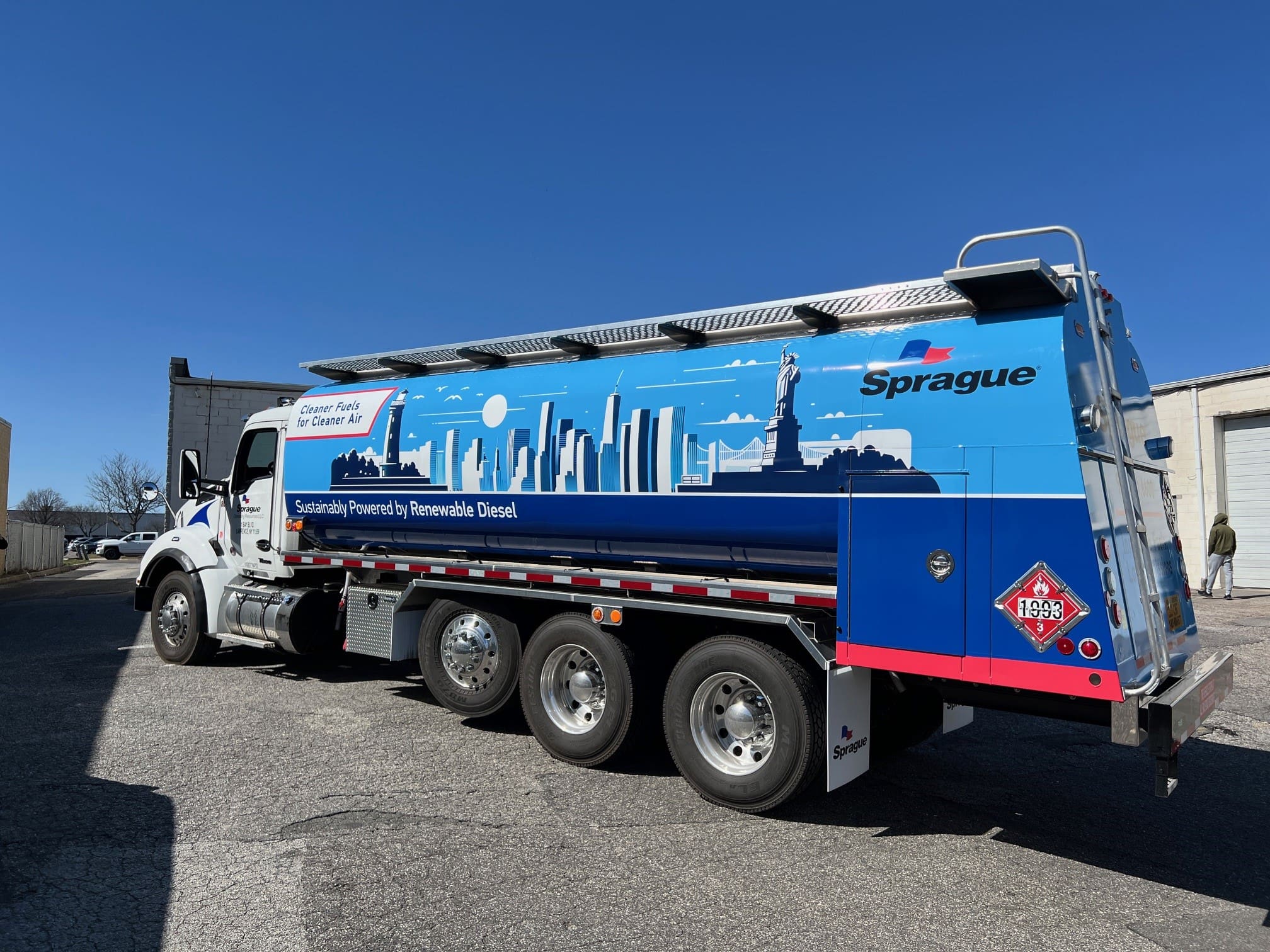 Sprague Energy fuel truck featuring a custom-painted city skyline design under a clear blue sky.